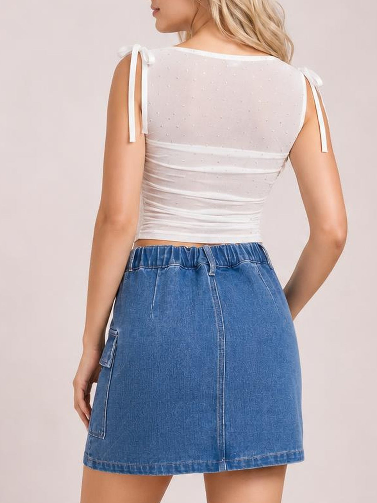 Model shown from behind wearing a blue pocketed denim skirt with a straight mini silhouette, elastic waistband, center seam, and hem stitching.