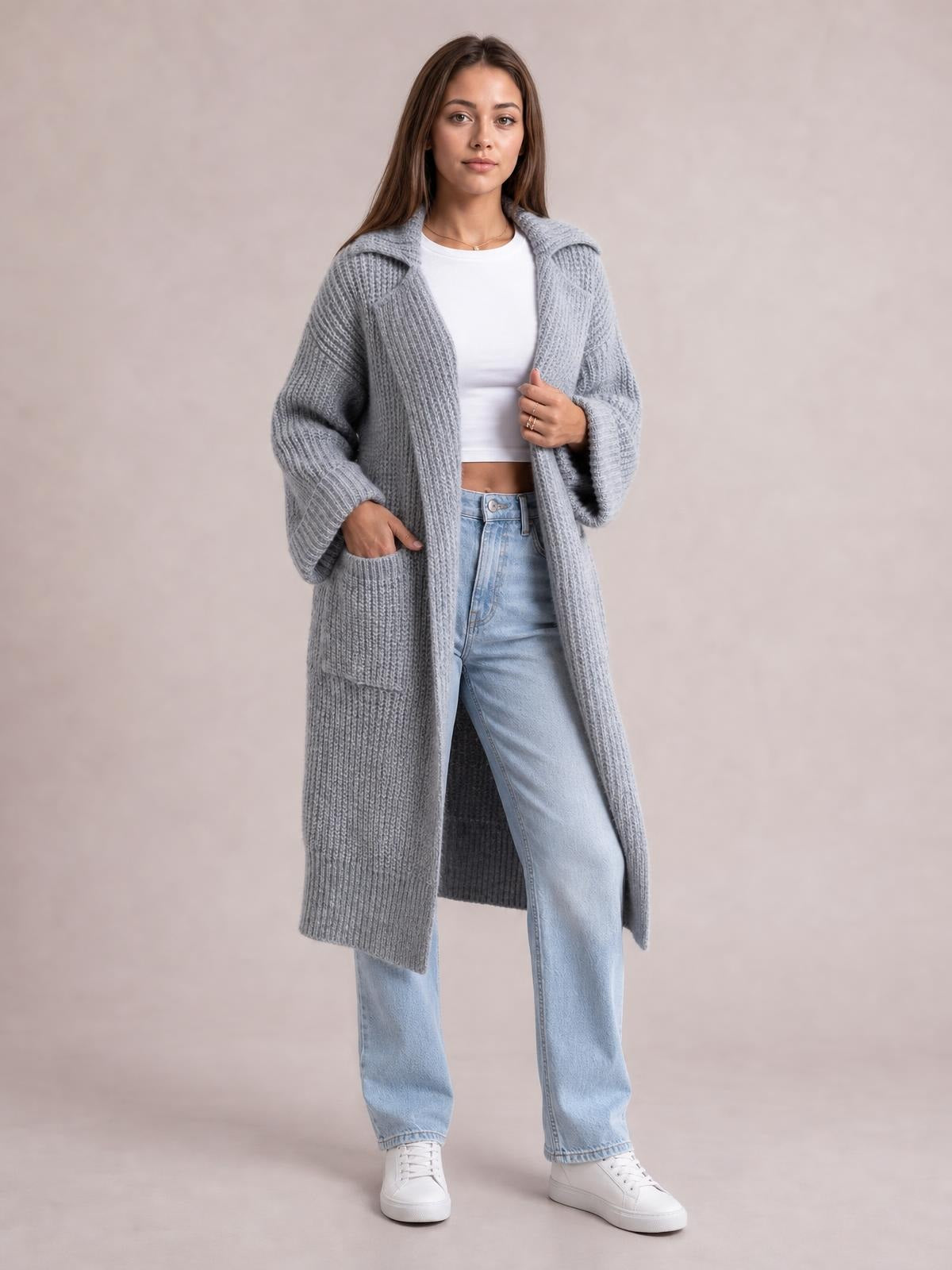 A model wears a light gray pocketed collared neck cardigan with dropped shoulders, ribbed texture, oversized sleeves, and a long relaxed silhouette.