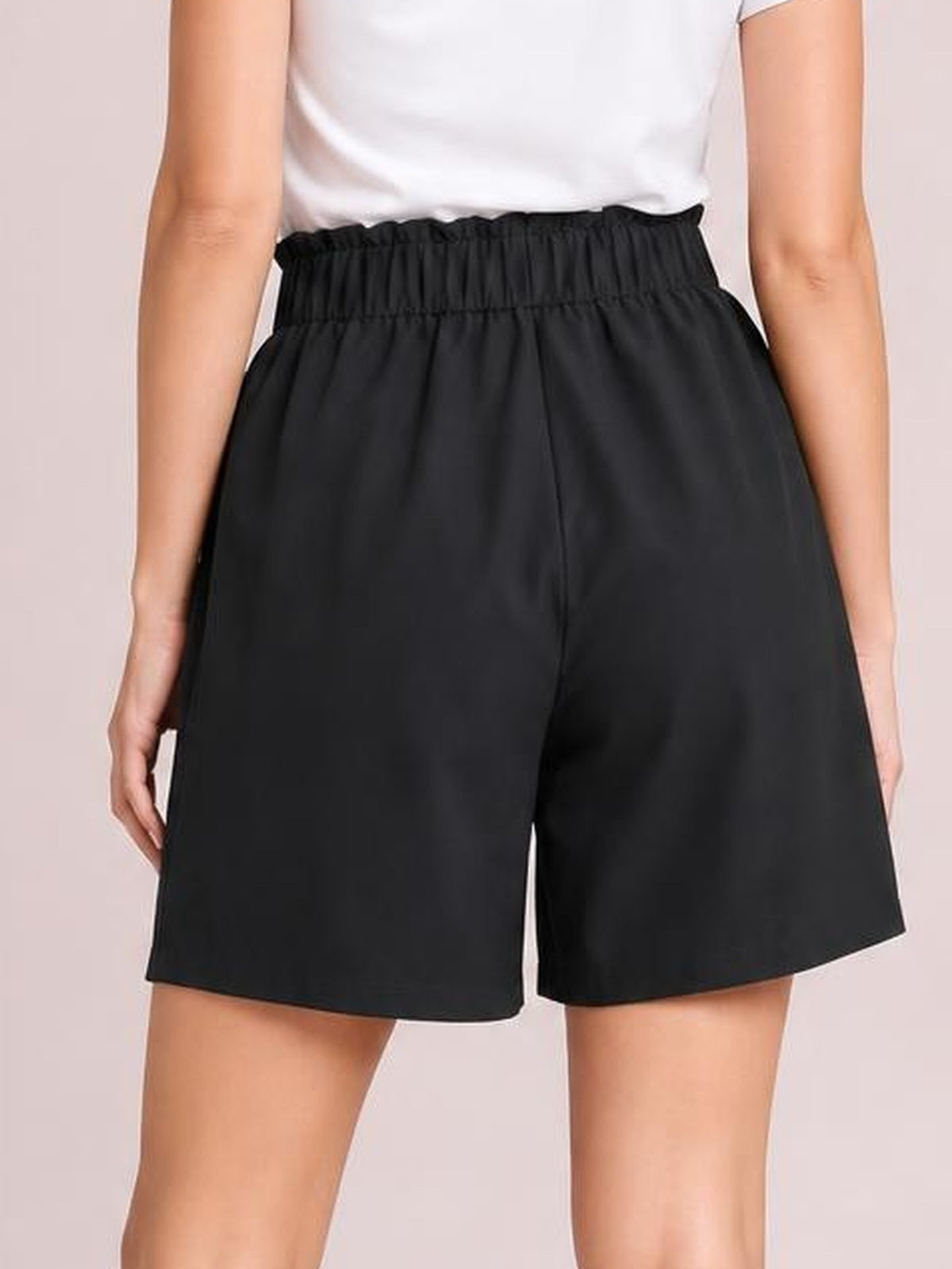 Model shown from the back wearing black pocketed shorts with a ruched half-elastic waistband, relaxed silhouette, and mid-thigh length.