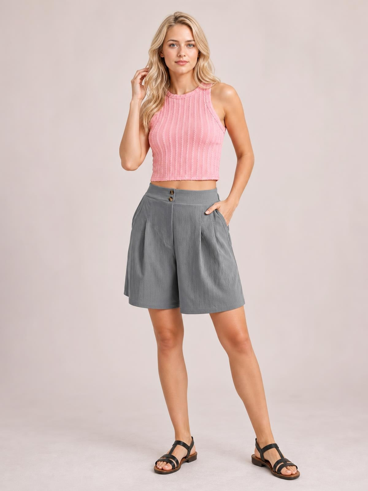 A model poses in gray pocketed shorts with a wide-leg silhouette, mid-thigh length, structured waistband, and front button closure.