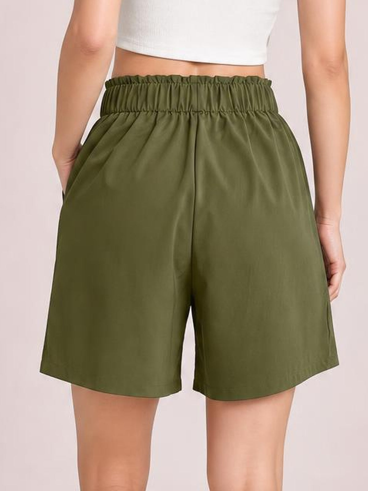 Model shown from behind wearing olive green pocketed shorts with a ruched half-elastic waistband, relaxed wide-leg silhouette, and straight hems.