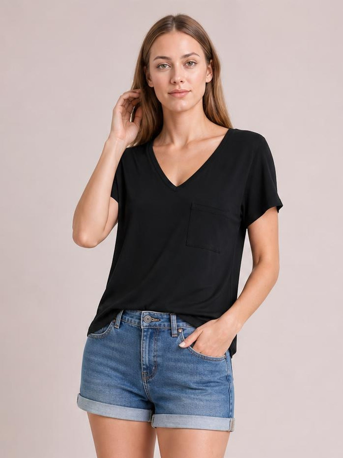 Model wears a black pocketed V-neck short sleeve T-shirt with a relaxed silhouette, slightly curved hem, and visible chest pocket.