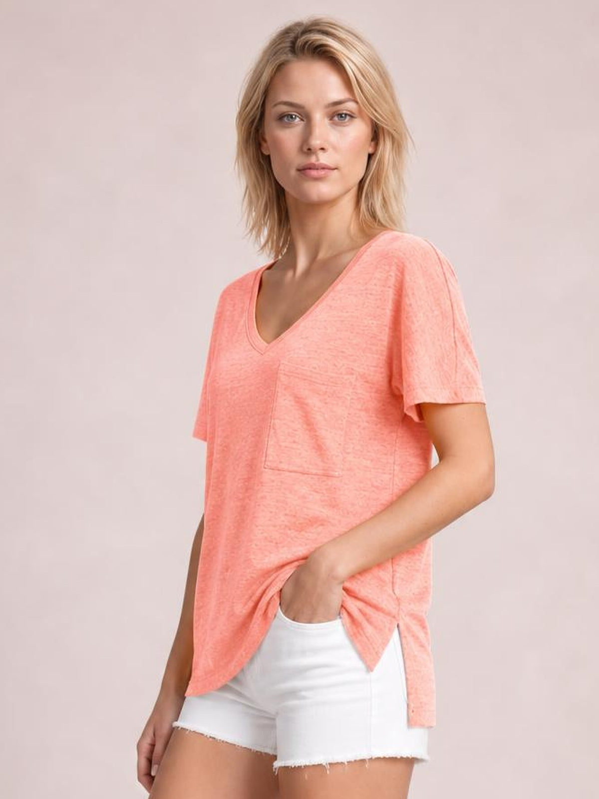 A model wears a coral heathered V-neck short-sleeve T-shirt with a relaxed silhouette, visible front pocket, and one hand tucked into the pocket.