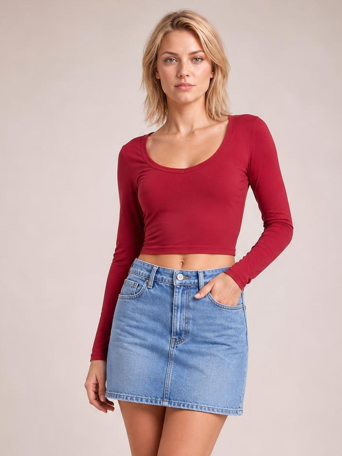 Model poses in a light blue high waist denim skirt with front pockets, belt loops, button closure, center seam, and a straight mini silhouette.
