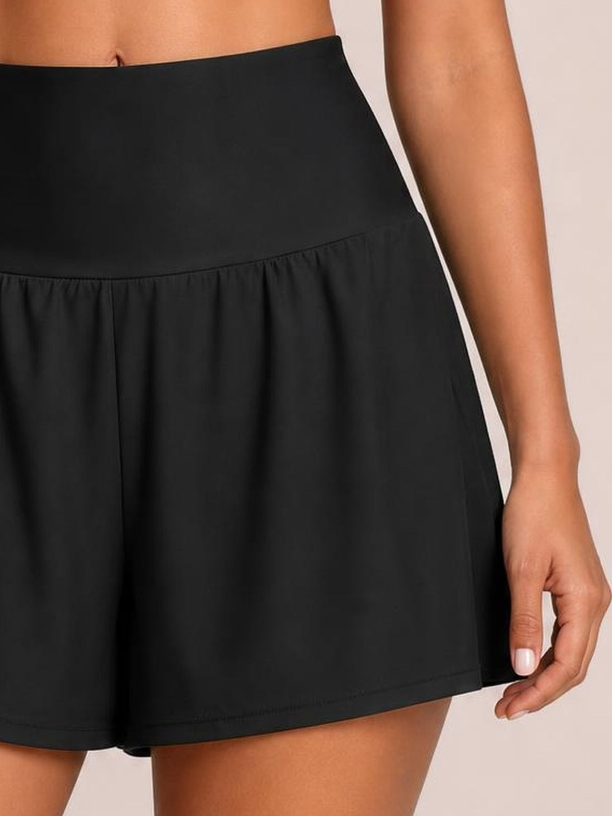 Model wears black pocketed high-waist swim shorts with a smooth waistband, relaxed A-line silhouette, and stitched hem, gently holding the side.