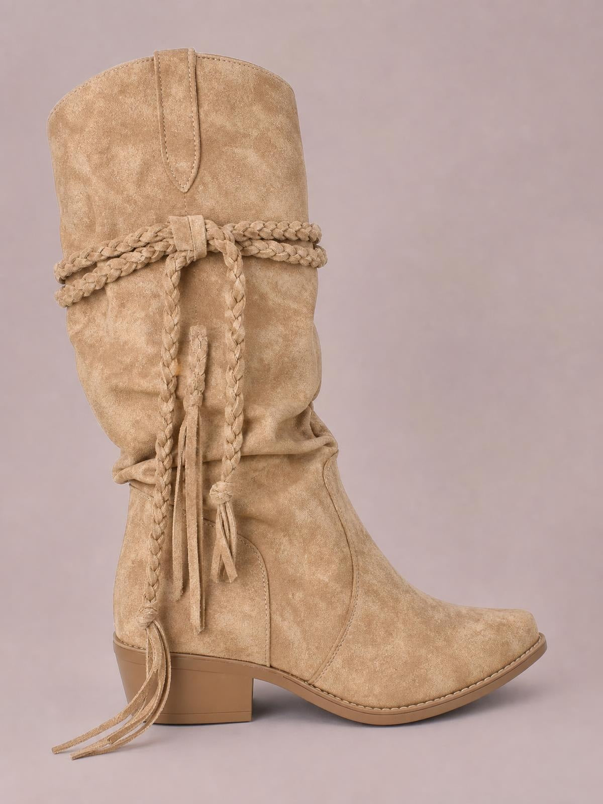 Tan PU leather point-toe boots feature a tall slouch shaft, braided wraparound ties with tassels, stitched panels, and a mid-height block heel.