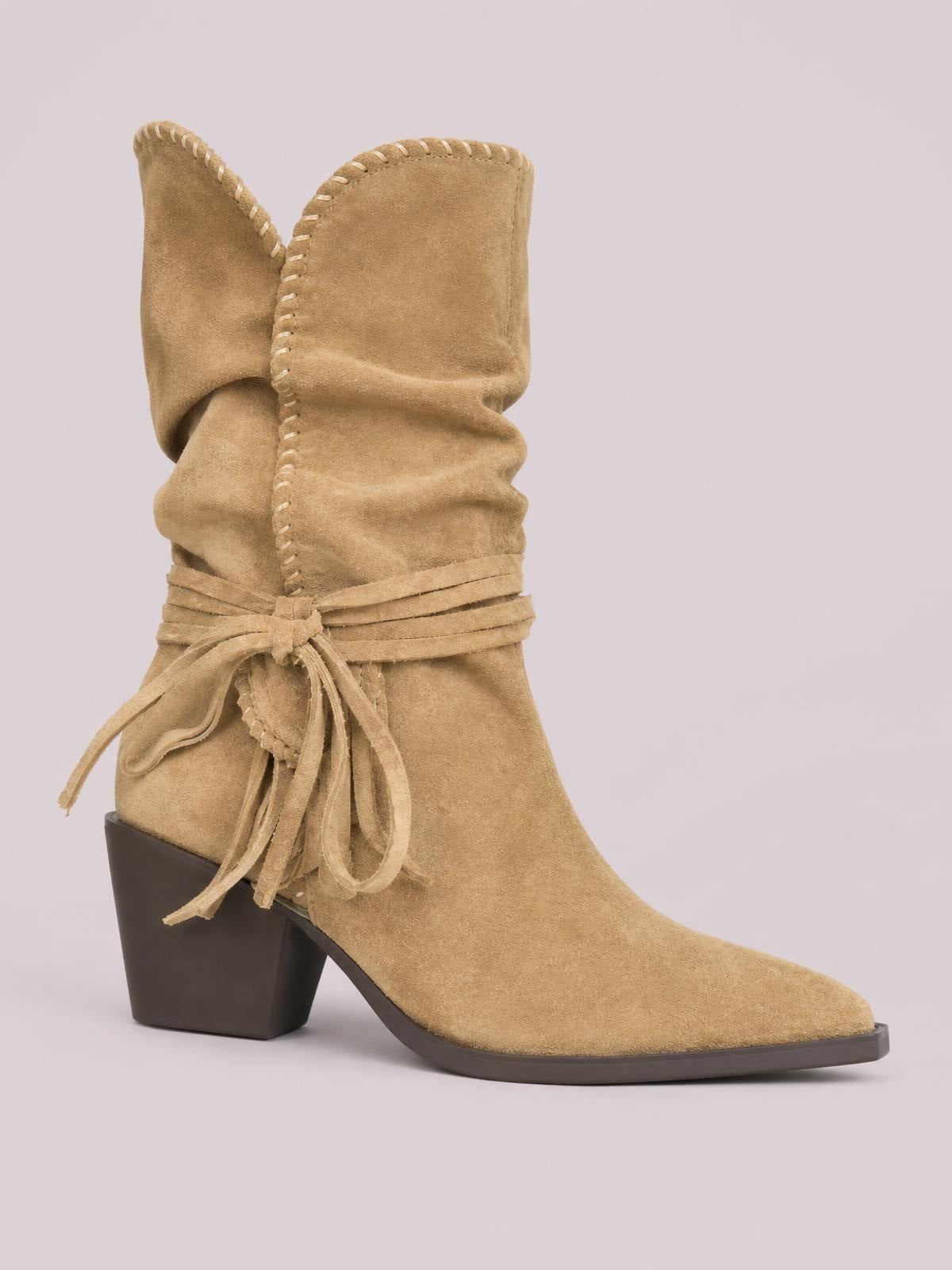 Tan suede point-toe block-heel boot with a slouchy shaft, wraparound tie detailing, visible contrast stitching, and a sturdy rubber sole.
