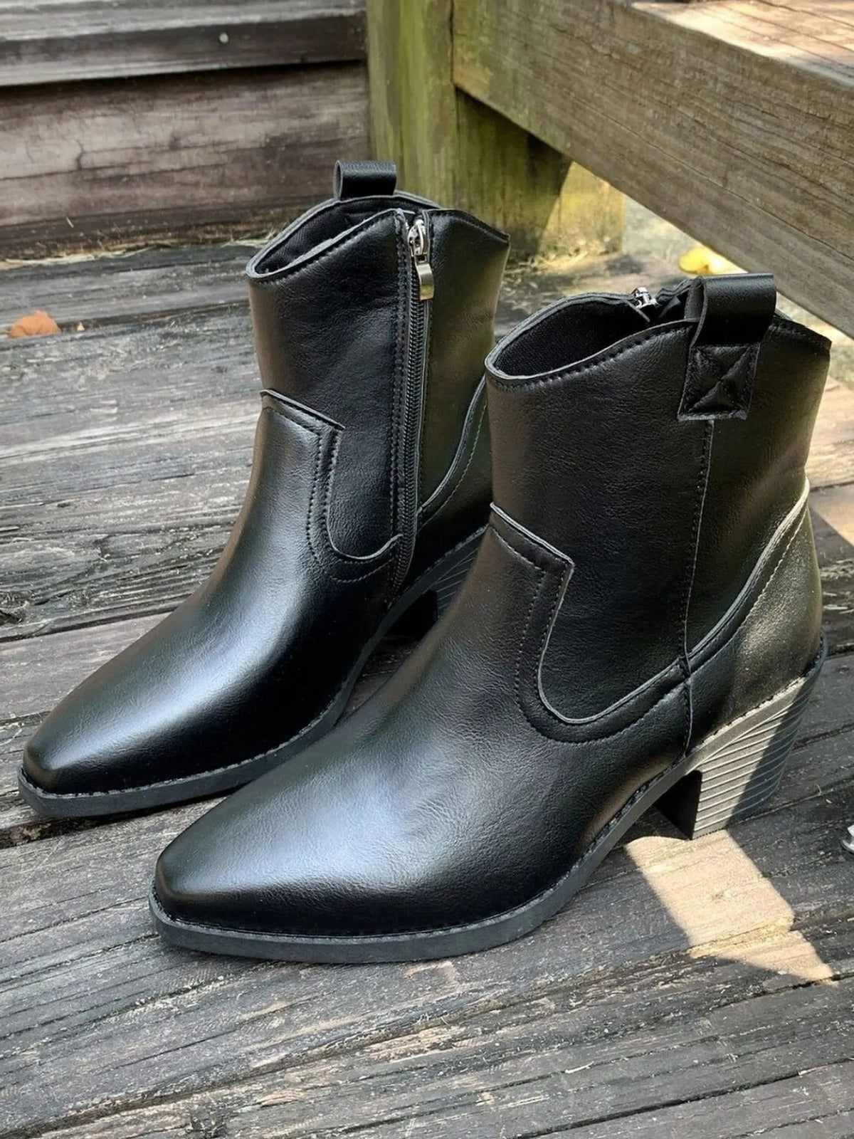 Black PU leather point-toe block heel boots with mid heels, side zippers, pull tabs, stitched panels, and textured rubber soles.