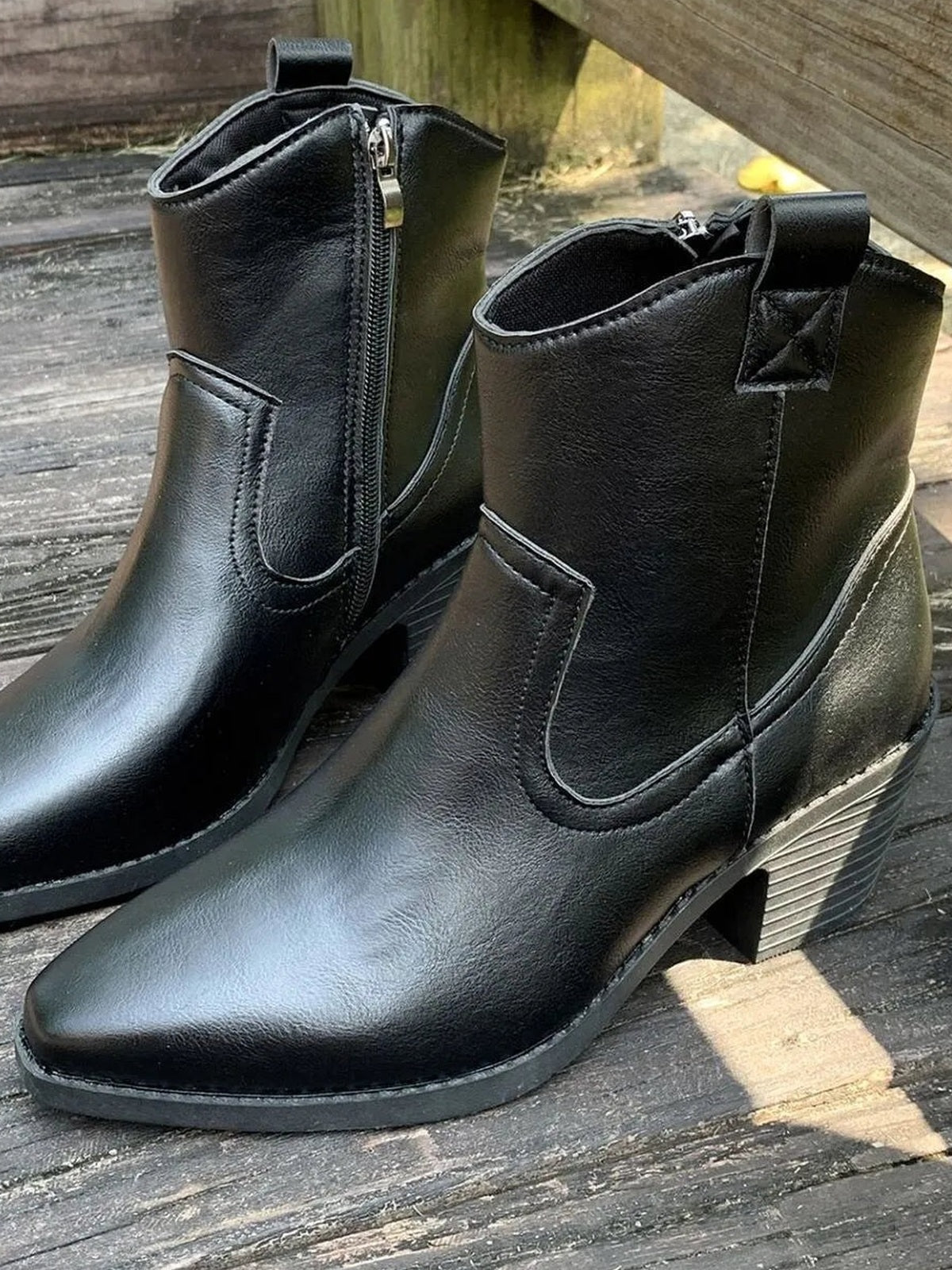 Black PU leather point toe block heel boots with side zippers, pull tabs, stitched overlays, and mid-height stacked heels.