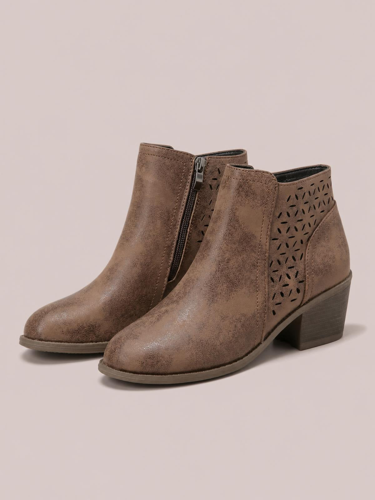 Taupe PU leather ankle boots feature pointed toes, mid-height block heels, side zippers, stitched panels, and decorative perforated cutouts.