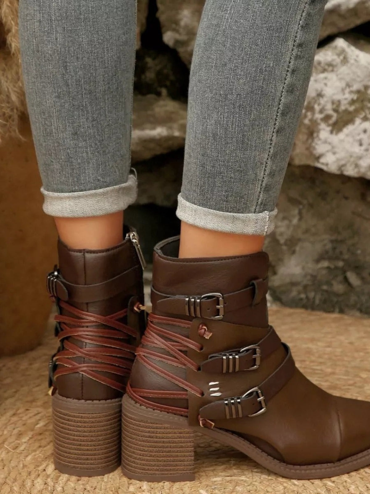 A model wears brown PU leather point-toe ankle boots with multiple buckle straps, wraparound laces, and sturdy mid-height block heels with textured soles.