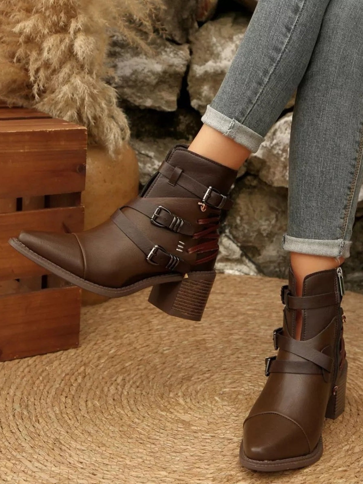 Model wears brown point-toe ankle boots with multiple buckle straps, side construction details, and sturdy mid-height block heels.