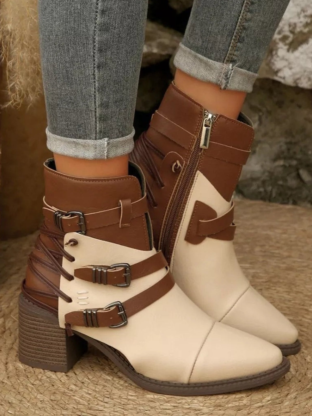 Cream and brown point-toe ankle boots with multiple buckle straps, side zippers, and chunky mid-height block heels worn with cuffed jeans.