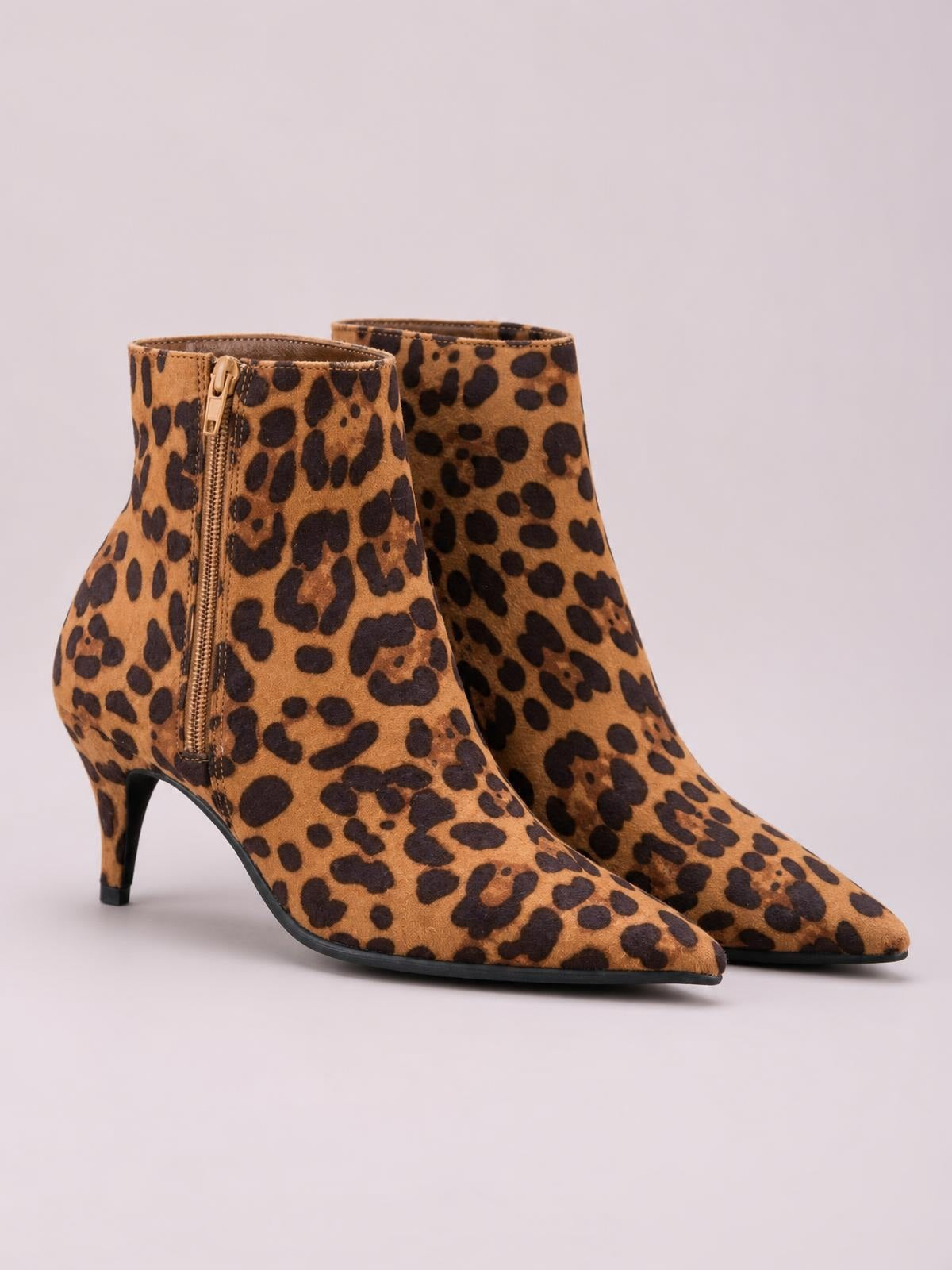 Leopard-print suede ankle boots in tan and black feature pointed toes, side zippers, sleek tapered silhouettes, and slim kitten heels.