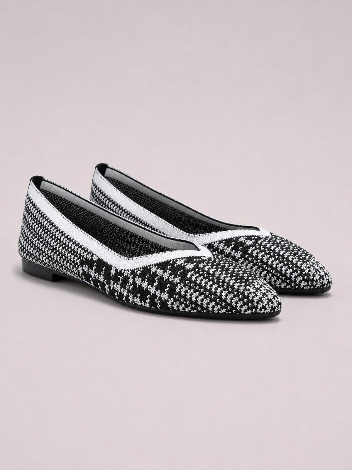 Black-and-white mesh flat slip-ons feature a pointed toe, woven patterned upper, low-profile silhouette, and slim black rubber soles.