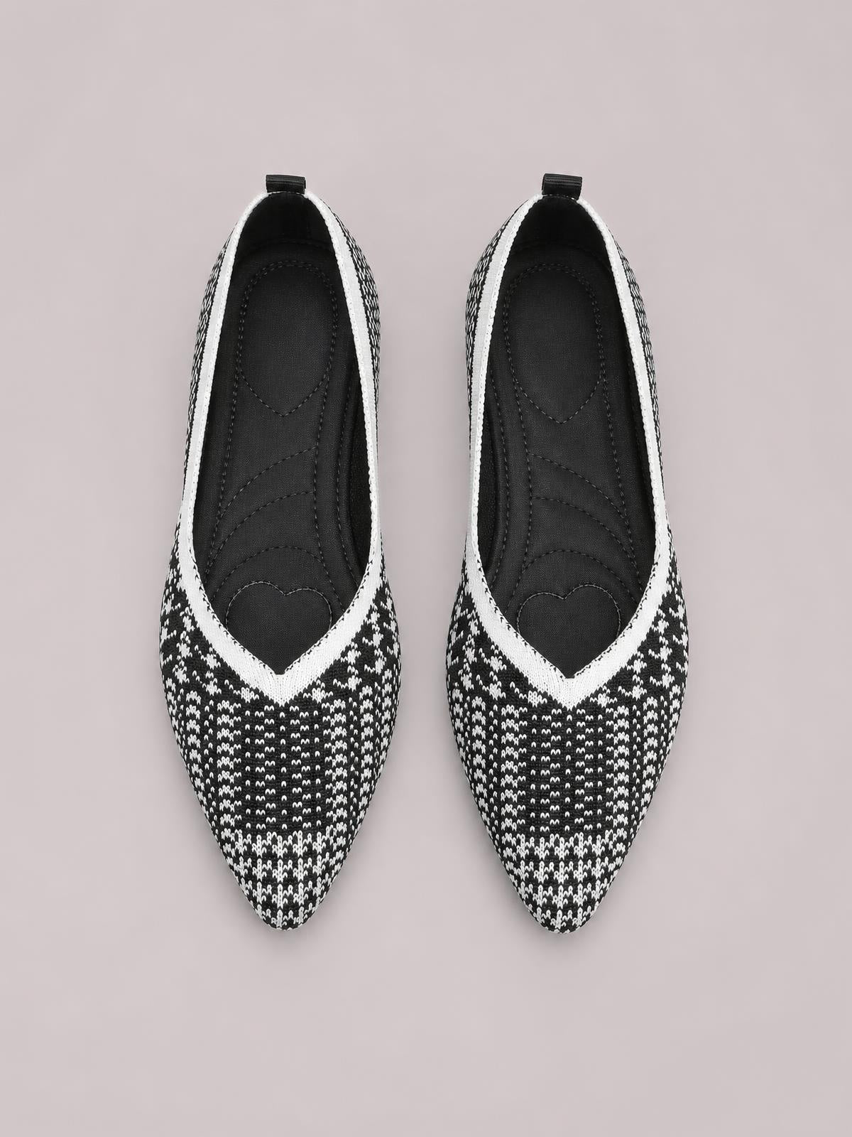 Pair of black-and-white patterned mesh flat slip-ons with pointed toes, contrast trim, open collars, rear pull tabs, and cushioned insoles.