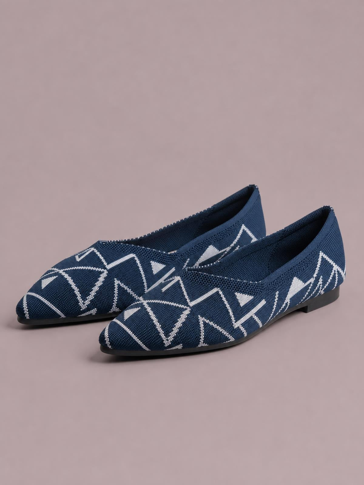 Navy mesh flat slip-on shoes feature pointed toes, white geometric knit patterns, low-profile silhouettes, and thin black rubber soles.