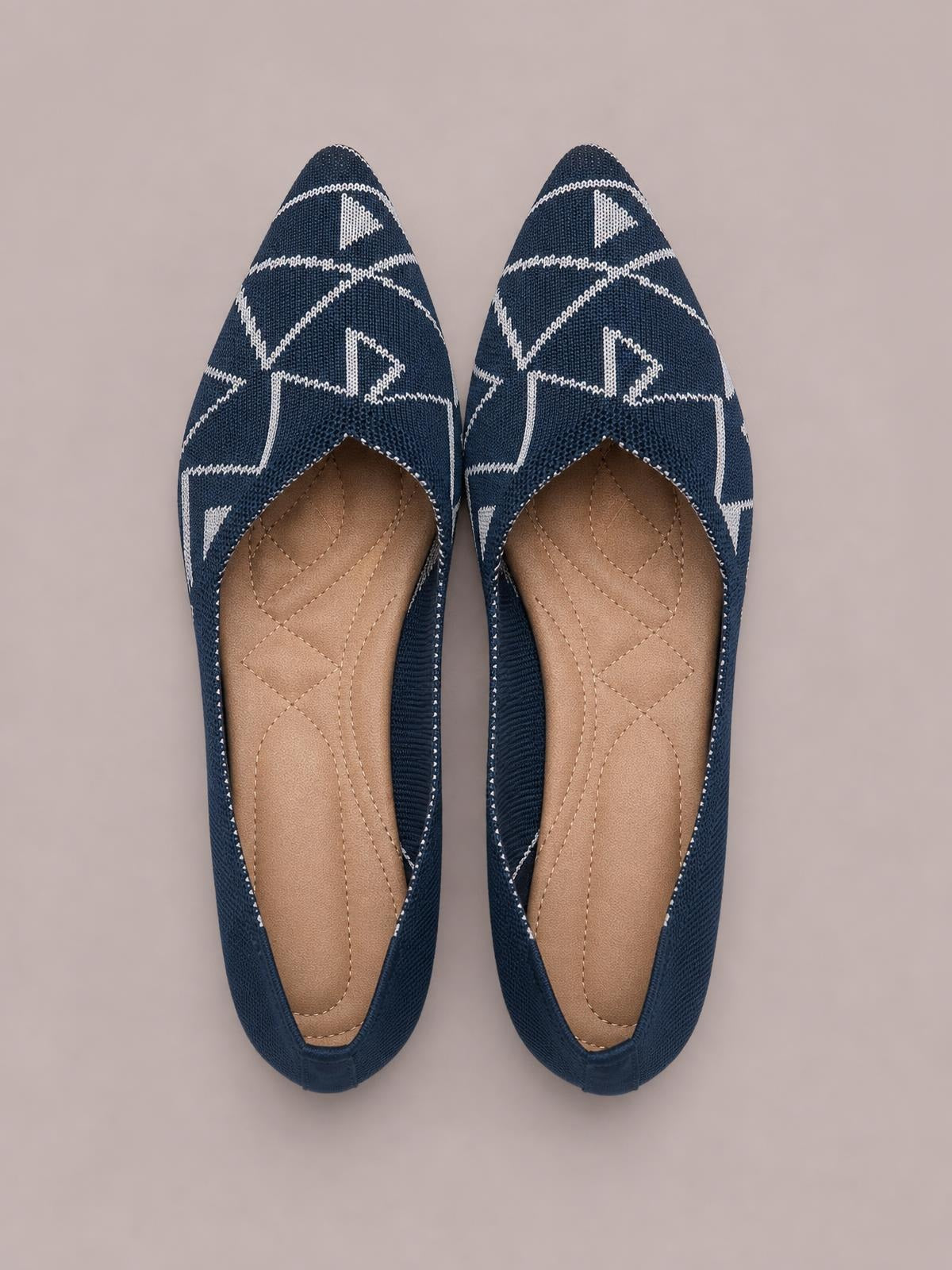 Pair of navy mesh point-toe flat slip-ons with white geometric stitching, open vamps, tan insoles, and low rubber soles.