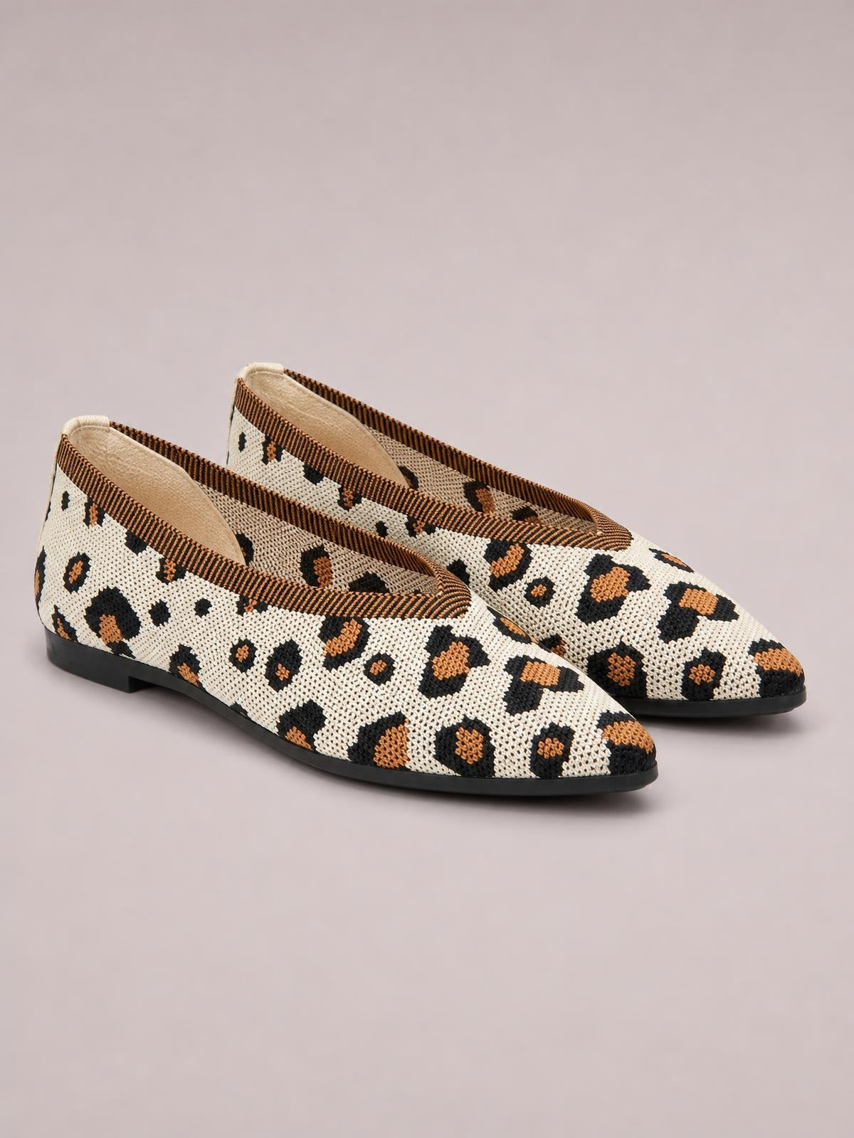 Point-toe mesh flat slip-on shoes in a cream, black, and tan leopard print feature a low silhouette and black rubber soles.
