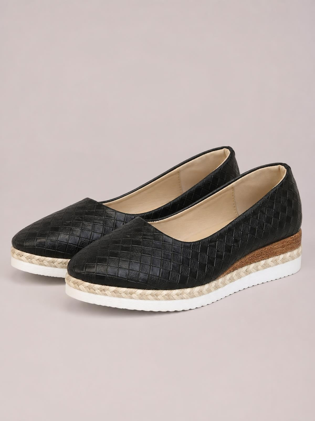 Black point-toe wedge loafers feature a textured quilted upper, low espadrille-style wedge heel, braided trim, and white platform sole.