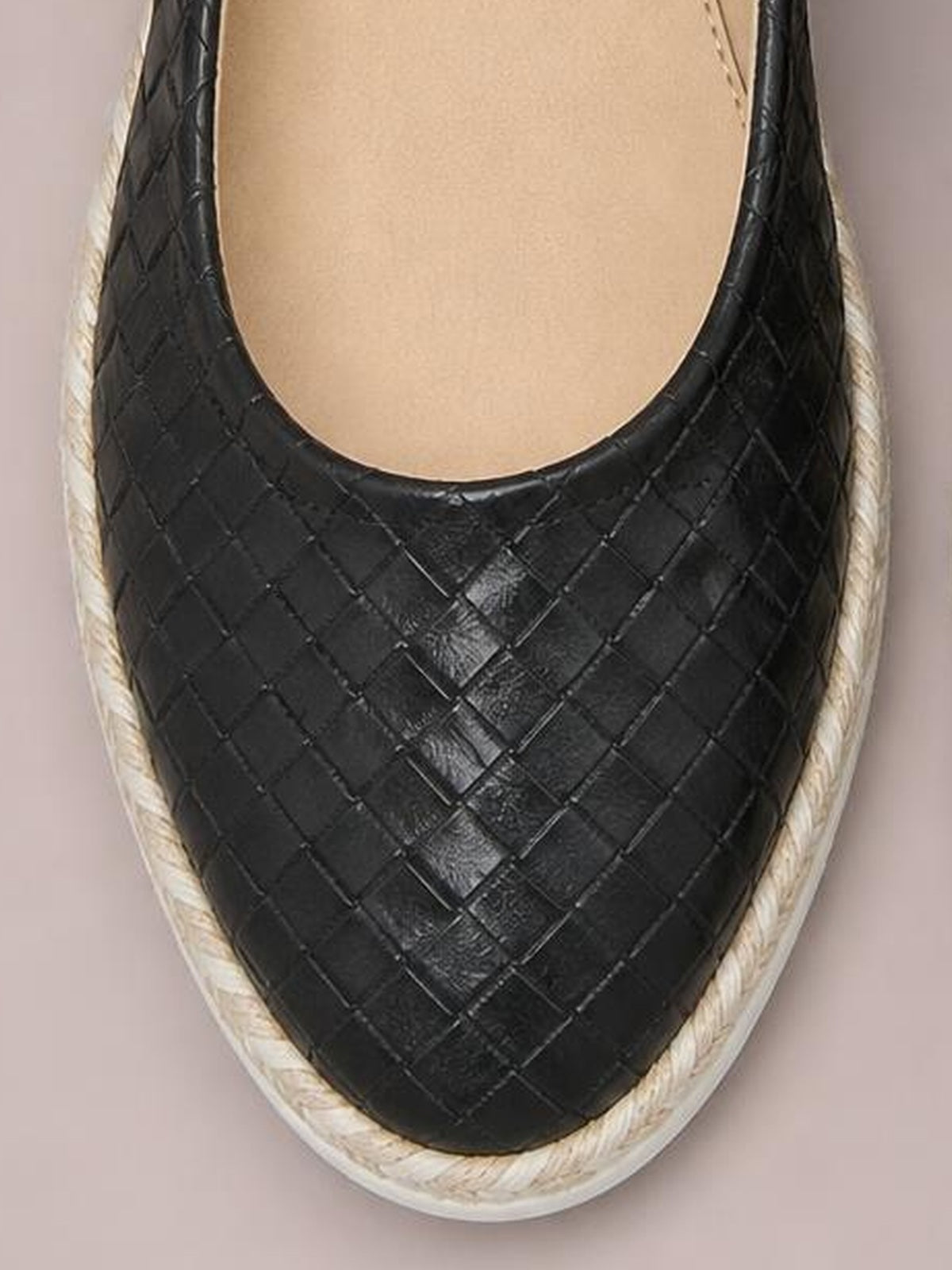 Black point-toe wedge loafer with a woven leather upper, rounded opening, and textured rope-style trim framing the low wedge sole.