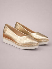 Gold metallic point-toe wedge loafers feature a textured diamond pattern, low wedge heels, braided trim, and thick white platform soles.