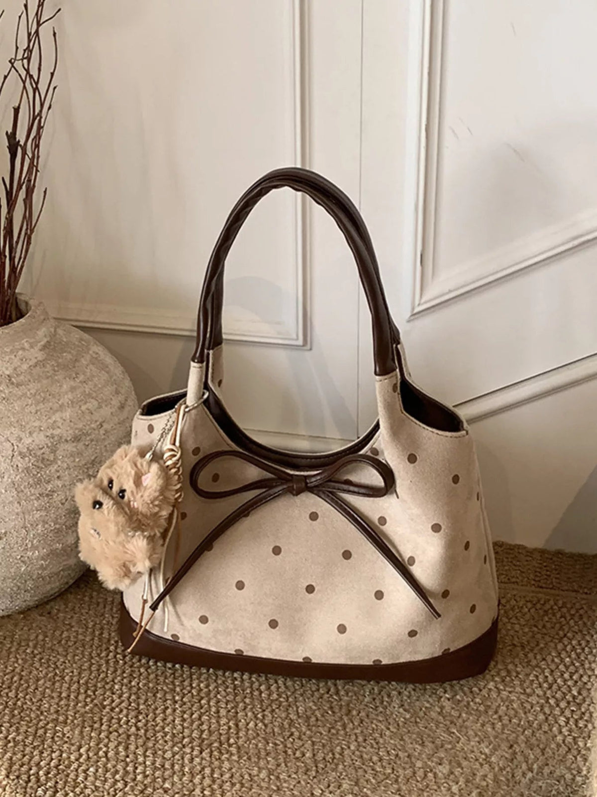 Medium cream PU leather shoulder bag with brown polka dots, contrasting trim, twin handles, a large front bow, and a plush charm.