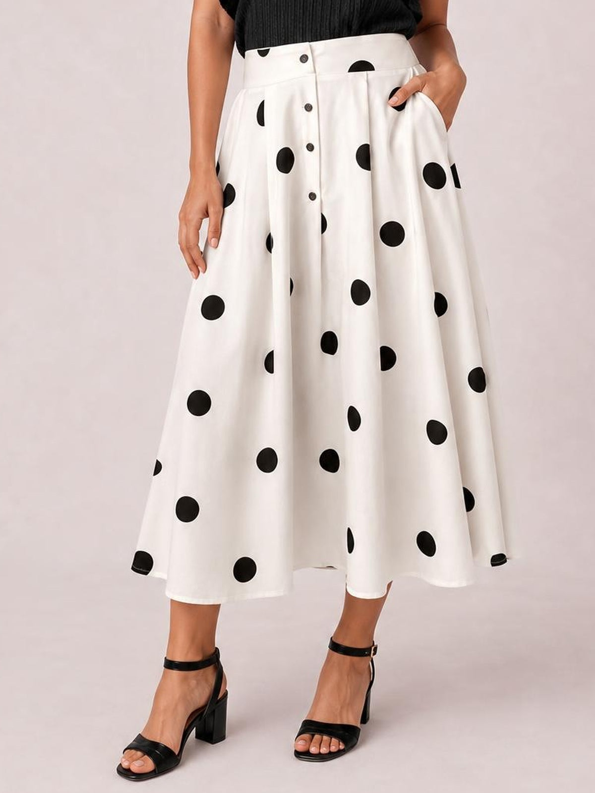 Model wearing a white polka dot skirt with black spots, button-front closure, high waist, pockets, and a flowing A-line midi silhouette.