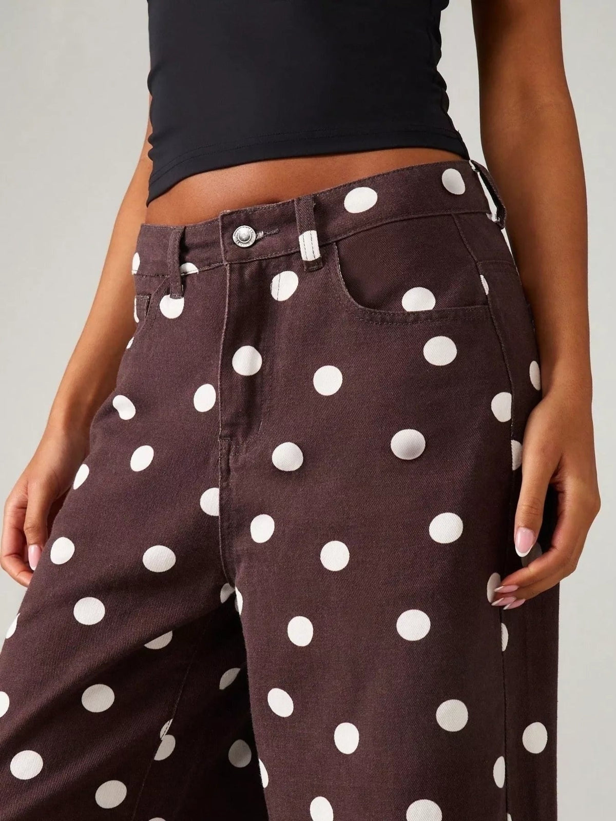 Model shown from the waist down wearing brown polka dot wide-leg jeans with a high waist, front button closure, belt loops, and pockets.