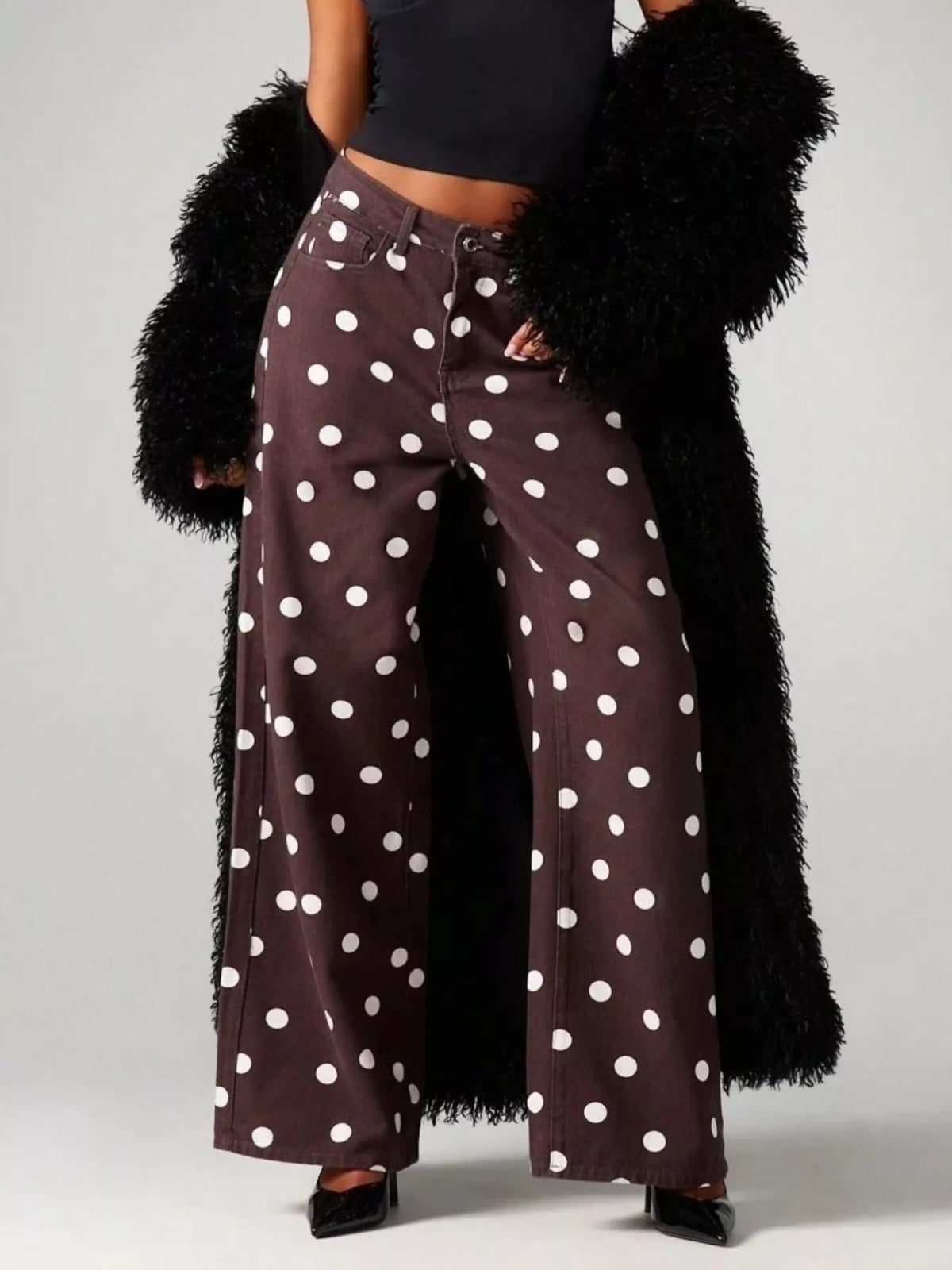 Model poses with hands in the pockets of brown polka dot wide-leg jeans, featuring a button fly, front pockets, and a full-length relaxed silhouette.