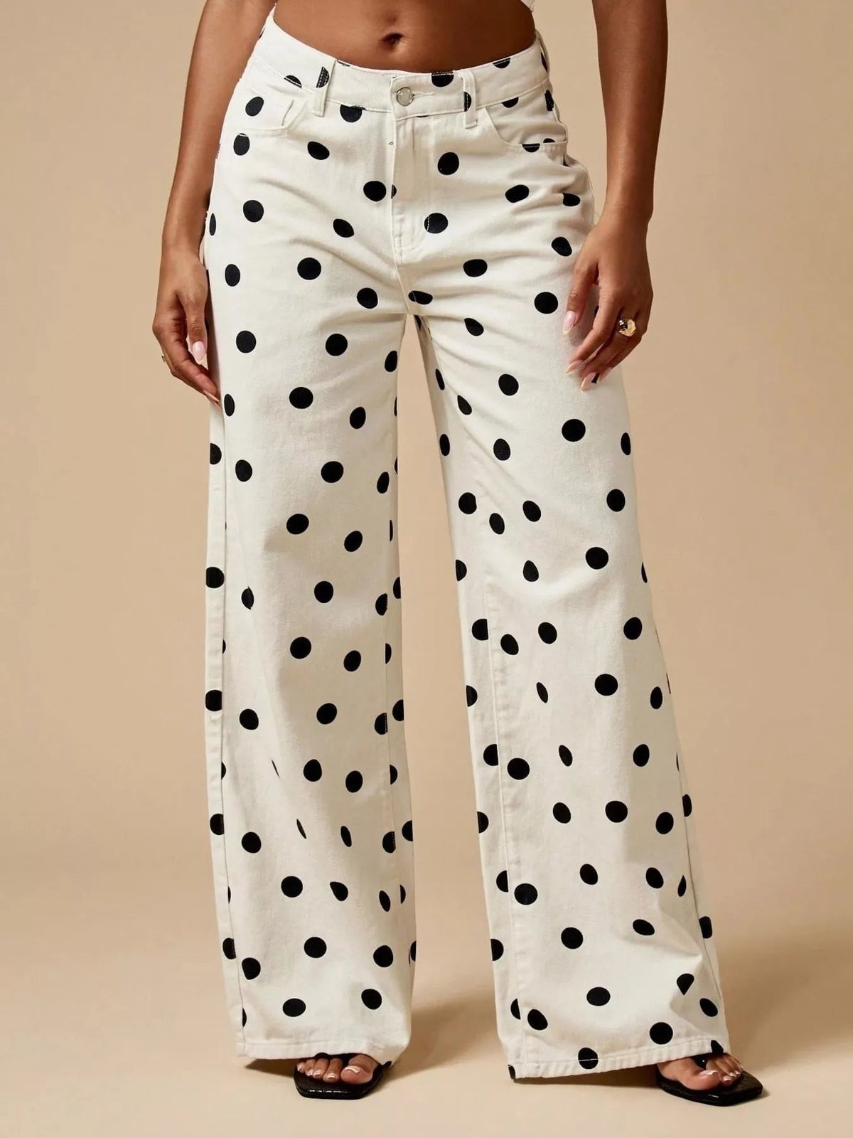 Model wearing white polka dot wide-leg jeans with a high waist, button fly, belt loops, front pockets, and a relaxed full-length silhouette.