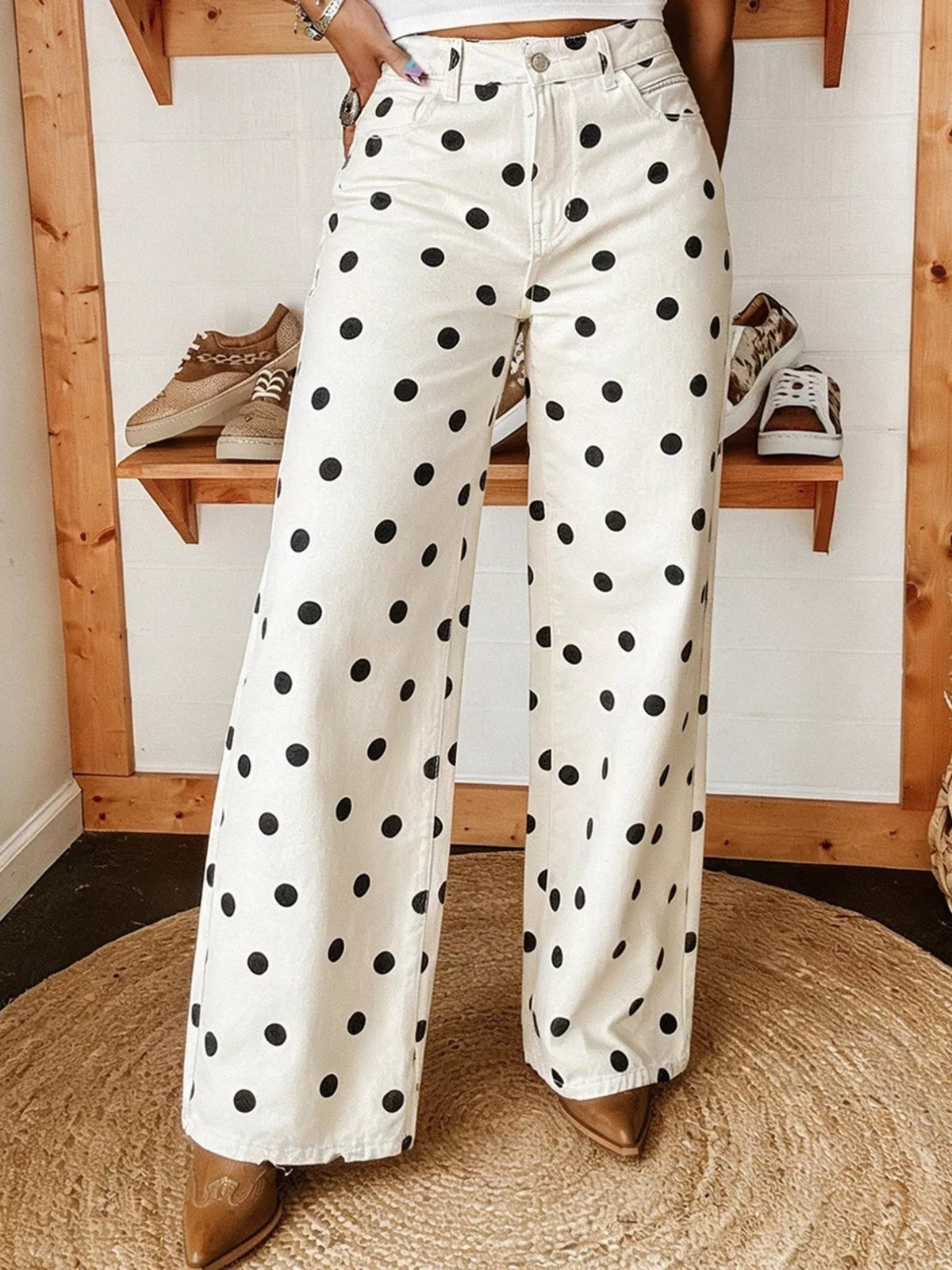 A model poses with one hand in the pocket, wearing white polka dot wide-leg jeans with a button fly, belt loops, and front pockets.