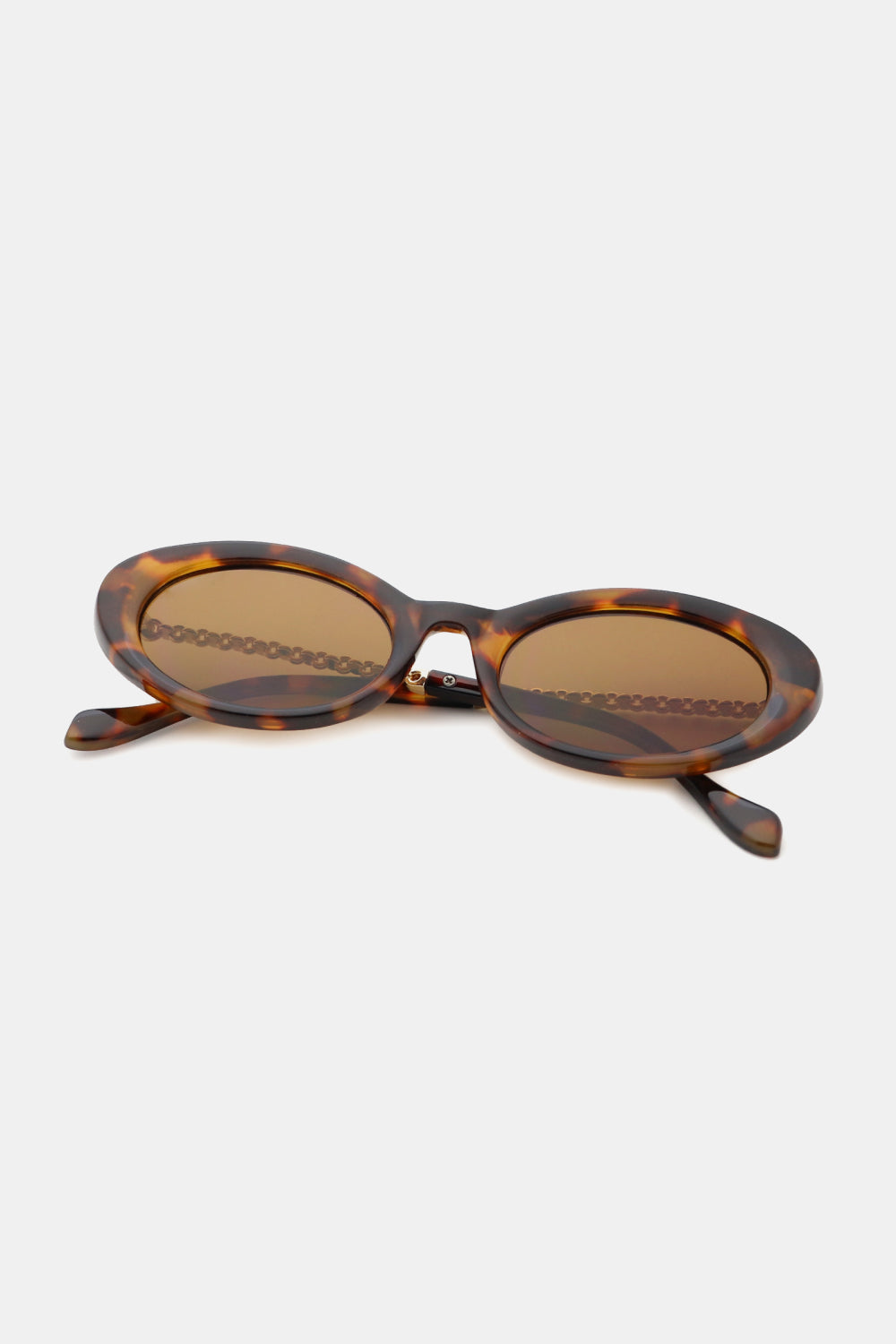 Tortoiseshell polycarbonate-frame cat-eye sunglasses feature rounded brown lenses, a softly upswept silhouette, and visible metal-plastic hybrid temples.