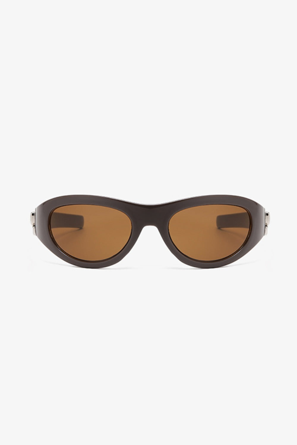 Dark brown polycarbonate cat-eye sunglasses feature rounded amber lenses, softly upswept corners, a streamlined bridge, and subtle metallic side detailing.