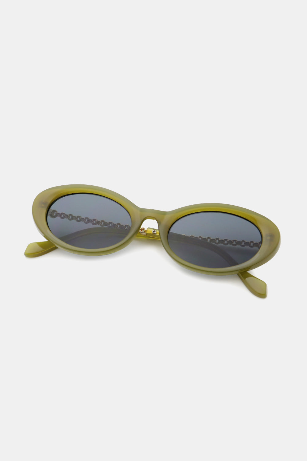Olive-green polycarbonate cat-eye sunglasses feature rounded dark lenses, a softly sculpted upswept frame, and contrasting metal-plastic hybrid temples.