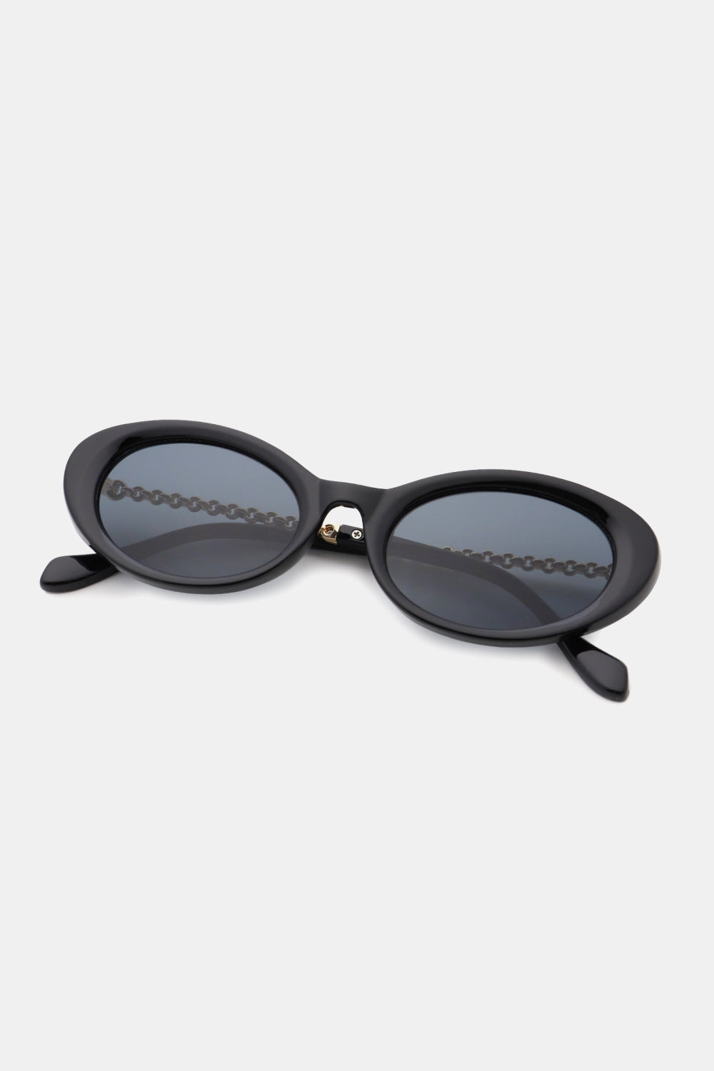 Black polycarbonate cat-eye sunglasses feature a softly sculpted, upswept frame, rounded smoky lenses, and sleek metal-plastic hybrid temples.