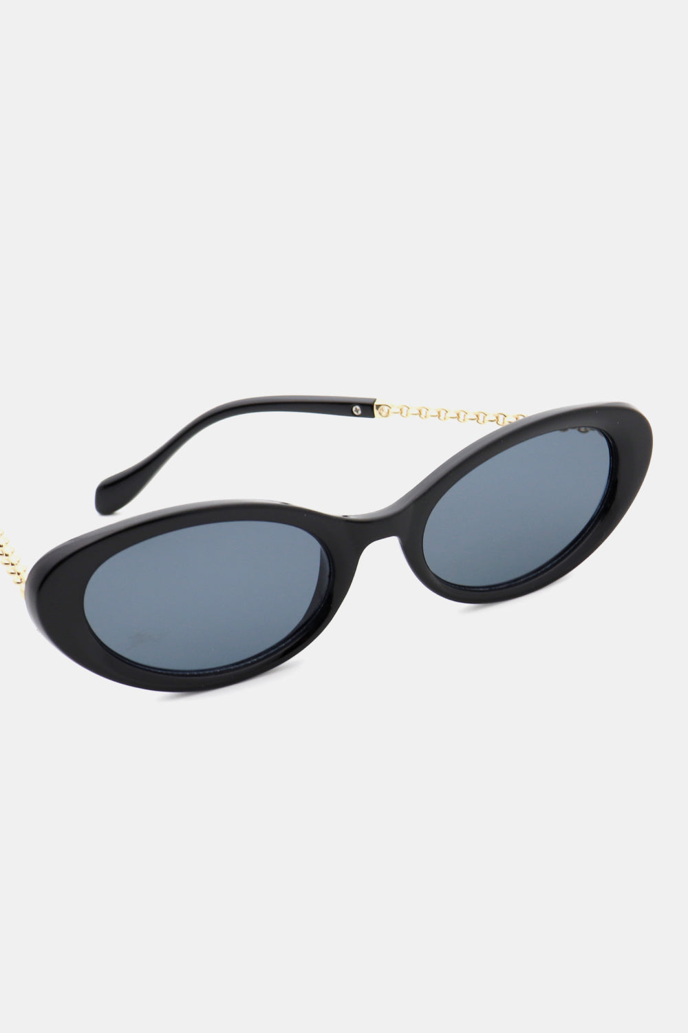 Black polycarbonate cat-eye sunglasses feature rounded blue-gray lenses, a softly upswept silhouette, and gold-toned linked detailing along the temples.