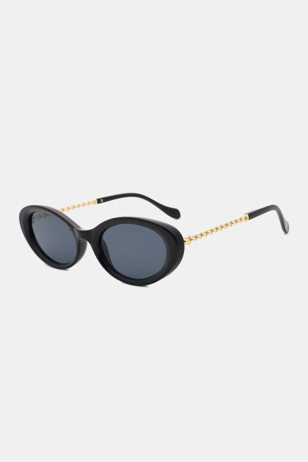 Black polycarbonate cat-eye sunglasses feature rounded dark lenses, a softly upswept sculpted silhouette, and contrasting gold chain-detail metal-plastic hybrid temples.