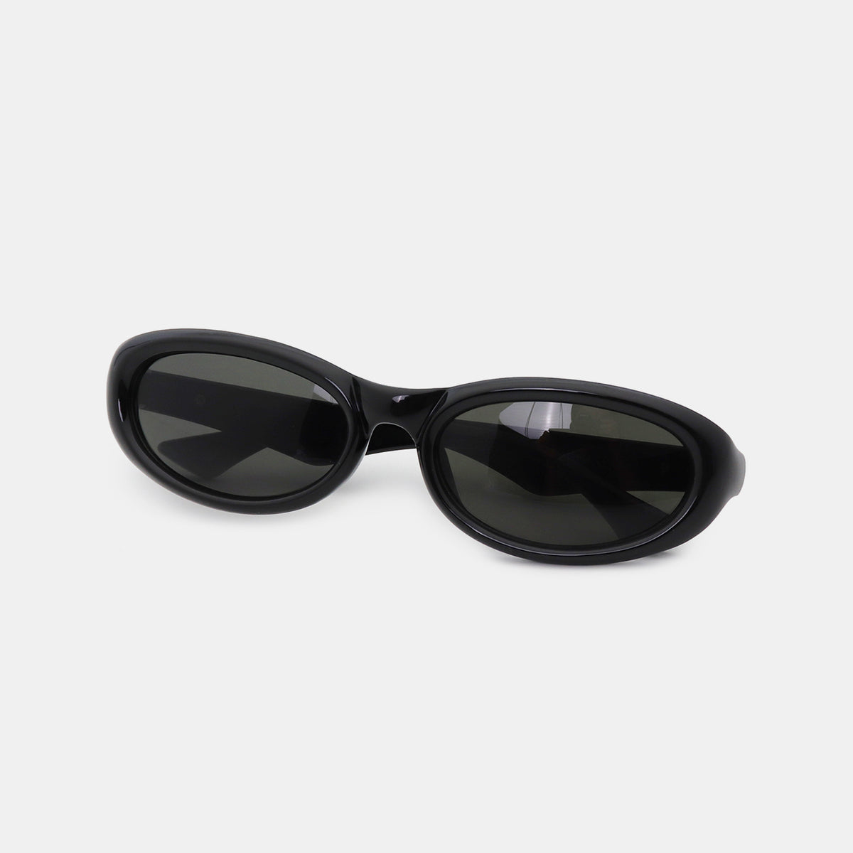 Glossy black polycarbonate cat-eye sunglasses feature softly sculpted oval lenses, a smooth frame, gently raised outer edges, and a shaped bridge.