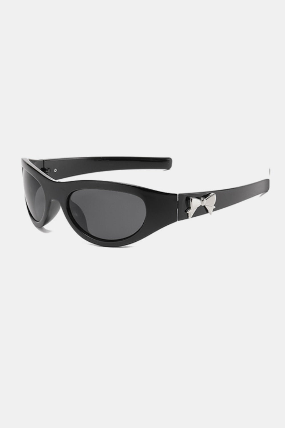Black polycarbonate cat-eye sunglasses feature rounded dark lenses, softly upswept frames, tapered temples, and a polished bow side detail.