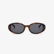 Brown tortoiseshell-inspired polycarbonate oval sunglasses feature softly rounded frames, dark lenses, and small star-like accents at the outer corners.