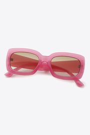 Pink polycarbonate rectangle sunglasses feature a bold, substantial frame with softly rounded corners, broad temples, and reddish-tinted lenses in a slightly angled display.