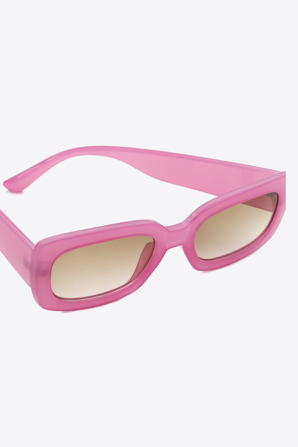 Bold pink polycarbonate rectangle sunglasses feature softly rounded corners, broad temples, substantial frames, and warm tinted lenses.