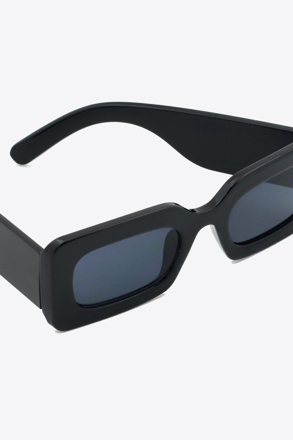 Black polycarbonate rectangle sunglasses feature softly rounded dark lenses, a bold structured frame, and substantial sculptural temples.