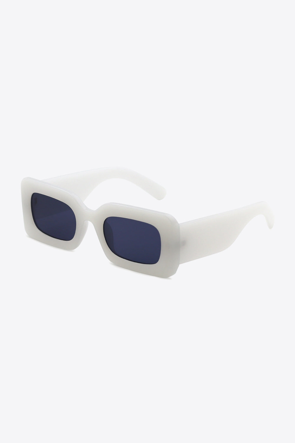 White polycarbonate rectangle sunglasses feature softly rounded dark lenses, a bold structured frame, and substantial sculptural temples shown in an angled view.