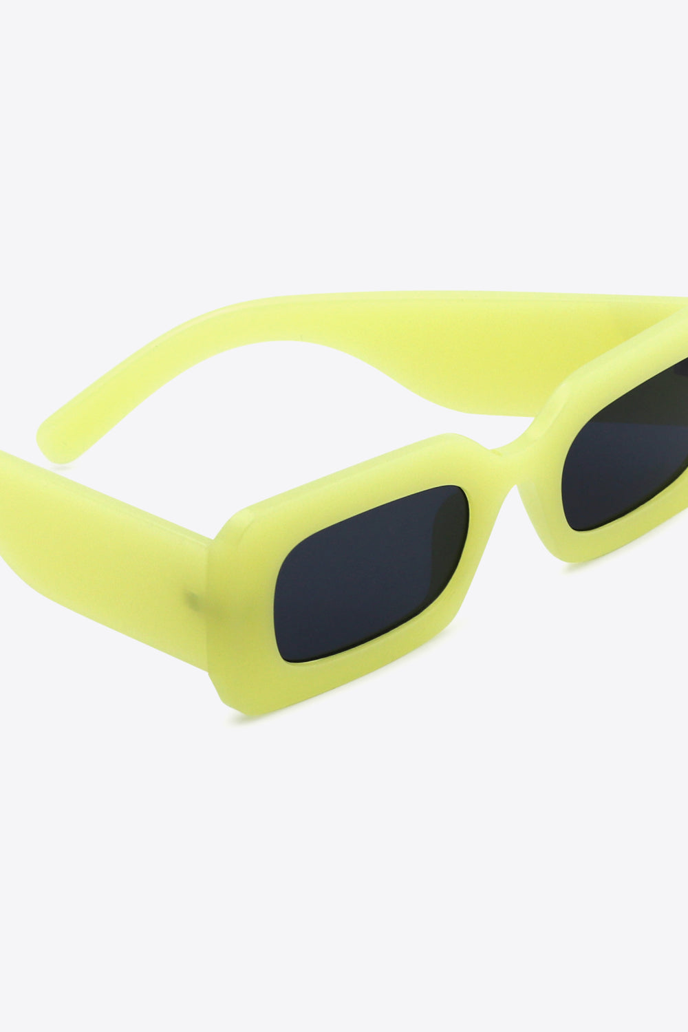 Bright yellow-green polycarbonate rectangle sunglasses feature softly rounded dark lenses, a bold structured frame, and substantial sculptural temples.