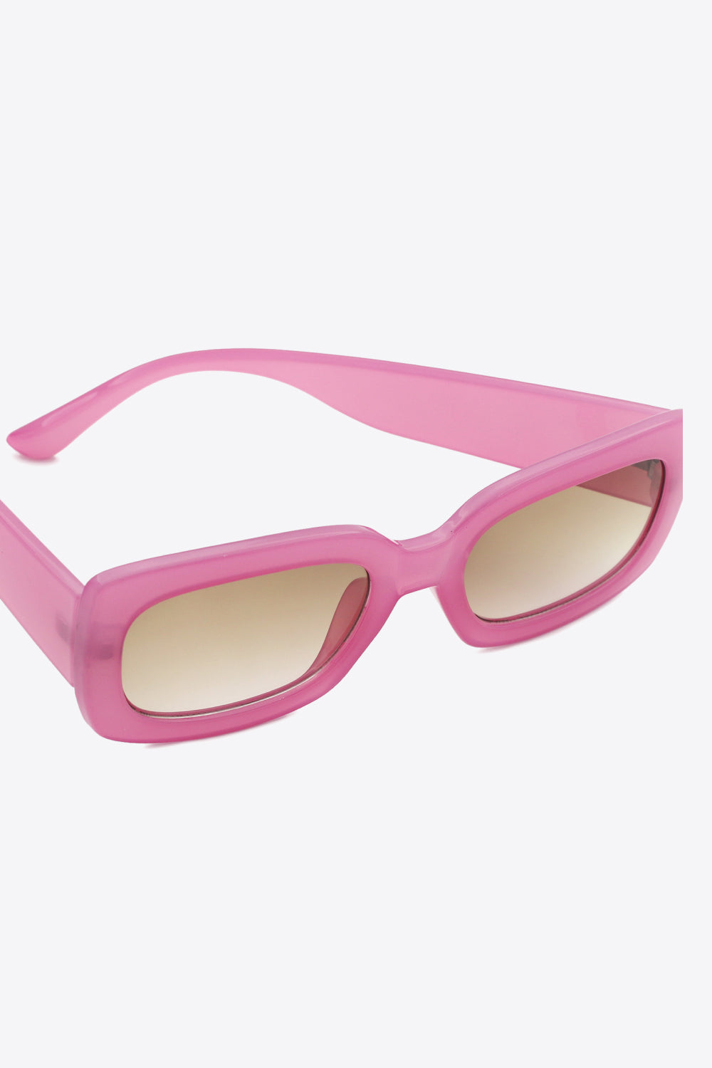 Bold pink polycarbonate rectangle sunglasses feature softly rounded corners, broad temples, substantial frames, and warm tinted lenses.