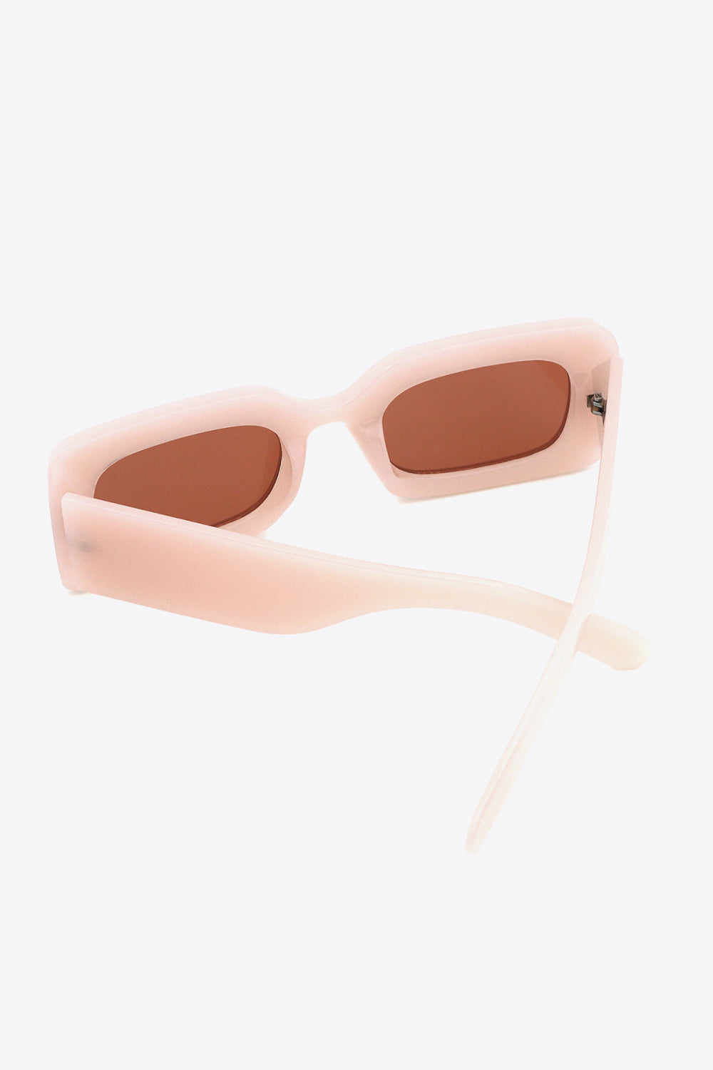 Translucent pale pink polycarbonate rectangle sunglasses feature softly rounded brown lenses and substantial sculptural temples for a bold, polished silhouette.
