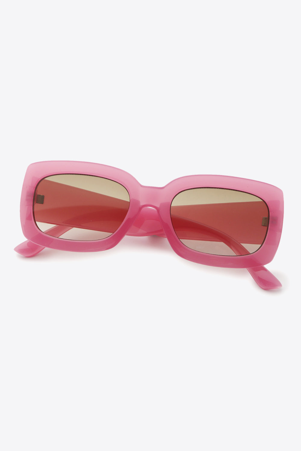 Pink polycarbonate rectangle sunglasses feature a bold, substantial frame with softly rounded corners, broad temples, and reddish-tinted lenses in a slightly angled display.