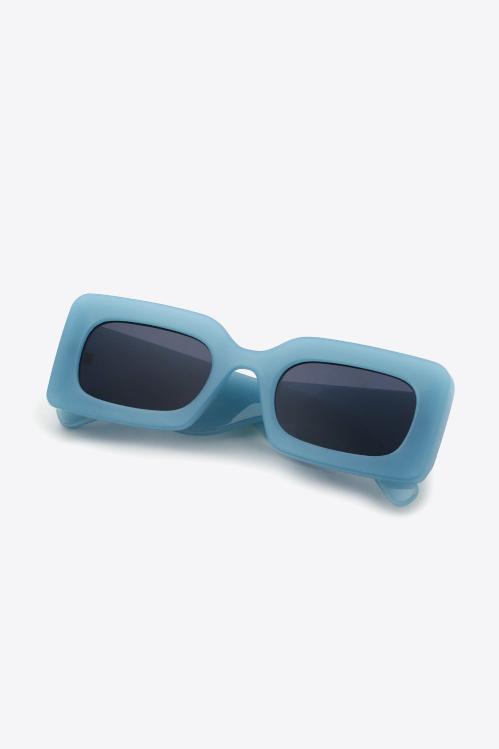 Blue polycarbonate rectangle sunglasses feature softly rounded dark lenses, a bold structured frame, and substantial sculptural temples.